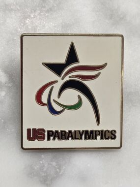 Team USA accessory is a square white enamel pin featuring the U.S. Paralympics